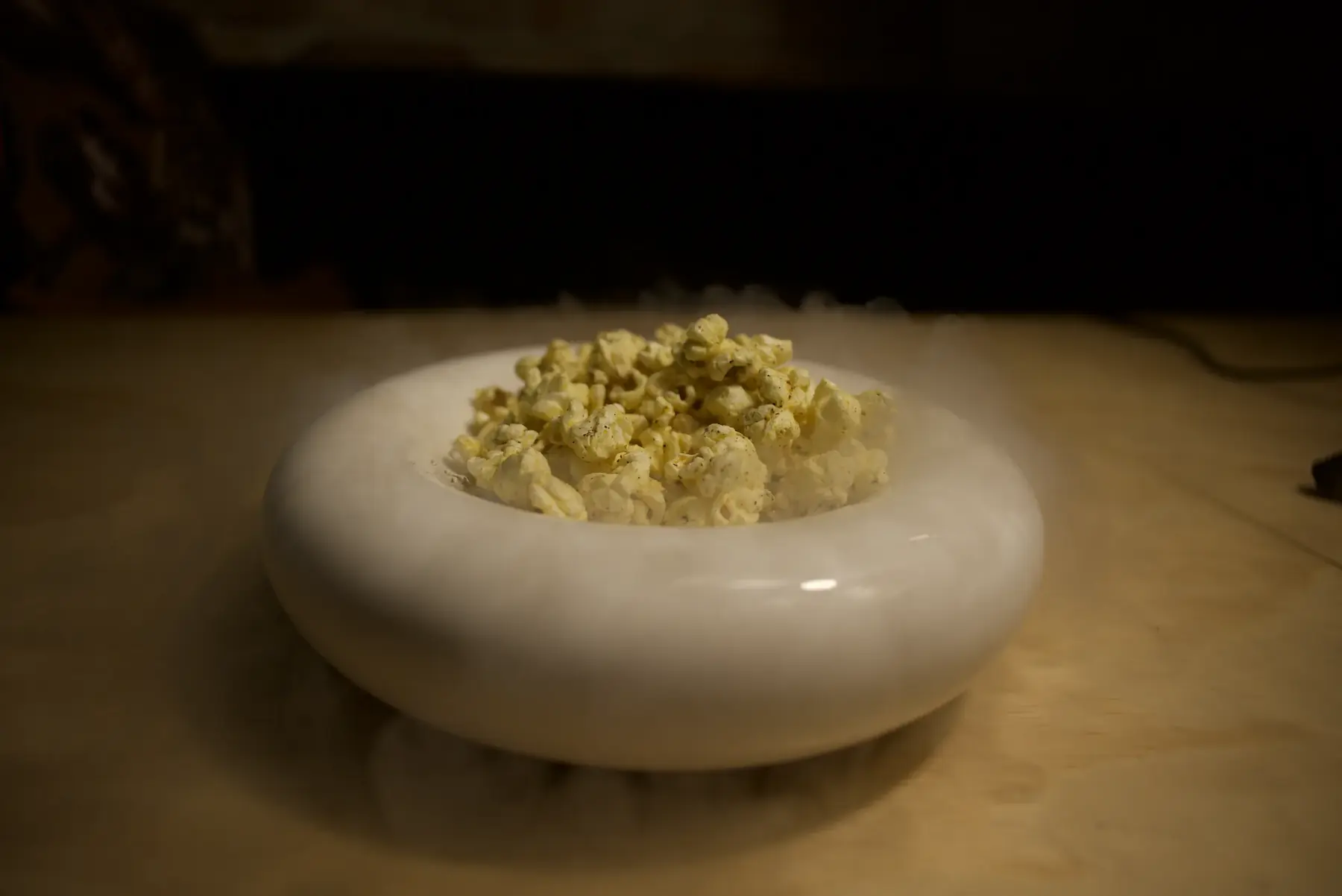 The frozen lime and corn popcorn snack in a white bowl, misting with liquid nitrogen