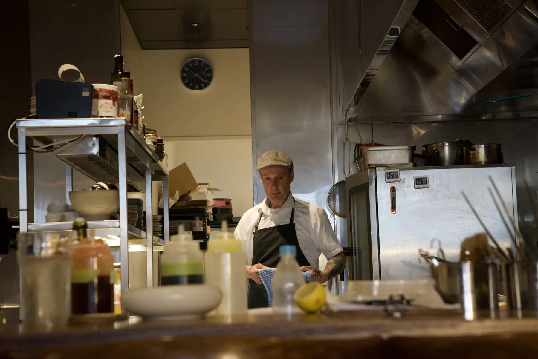 A chef in a cap and apron behind the pass in Little Honey’s open kitchen
