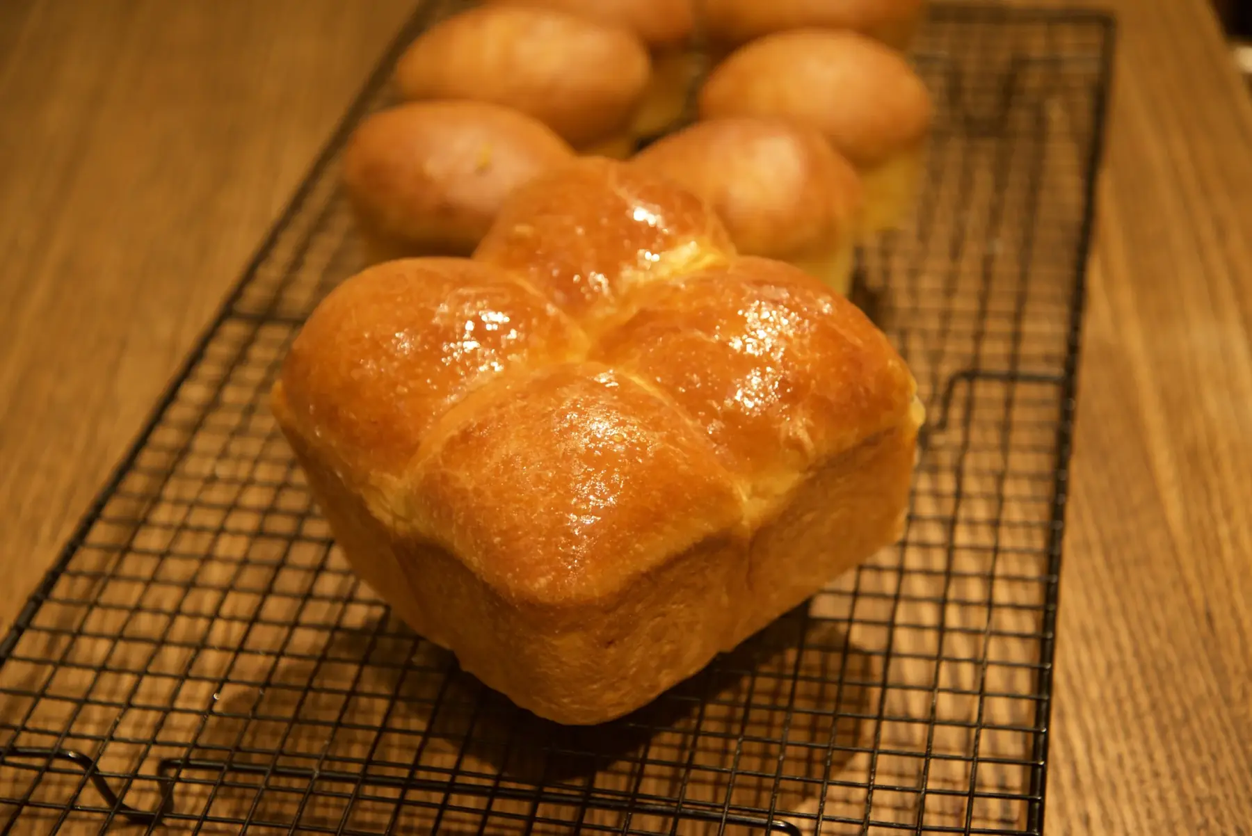 House-baked brioche buns, glazed and cooling on a wire rack