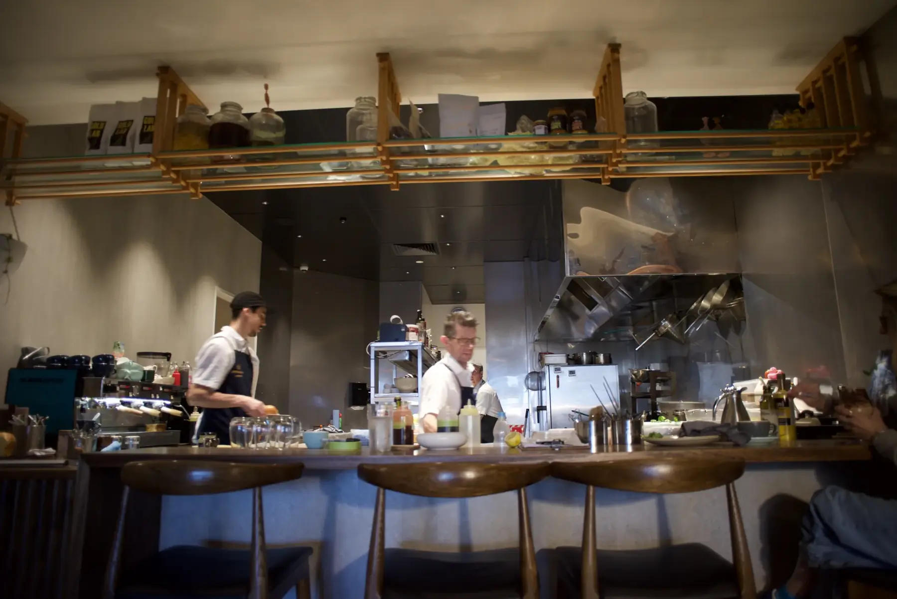 The open kitchen at Little Honey, seen from the counter stools, with two chefs at work