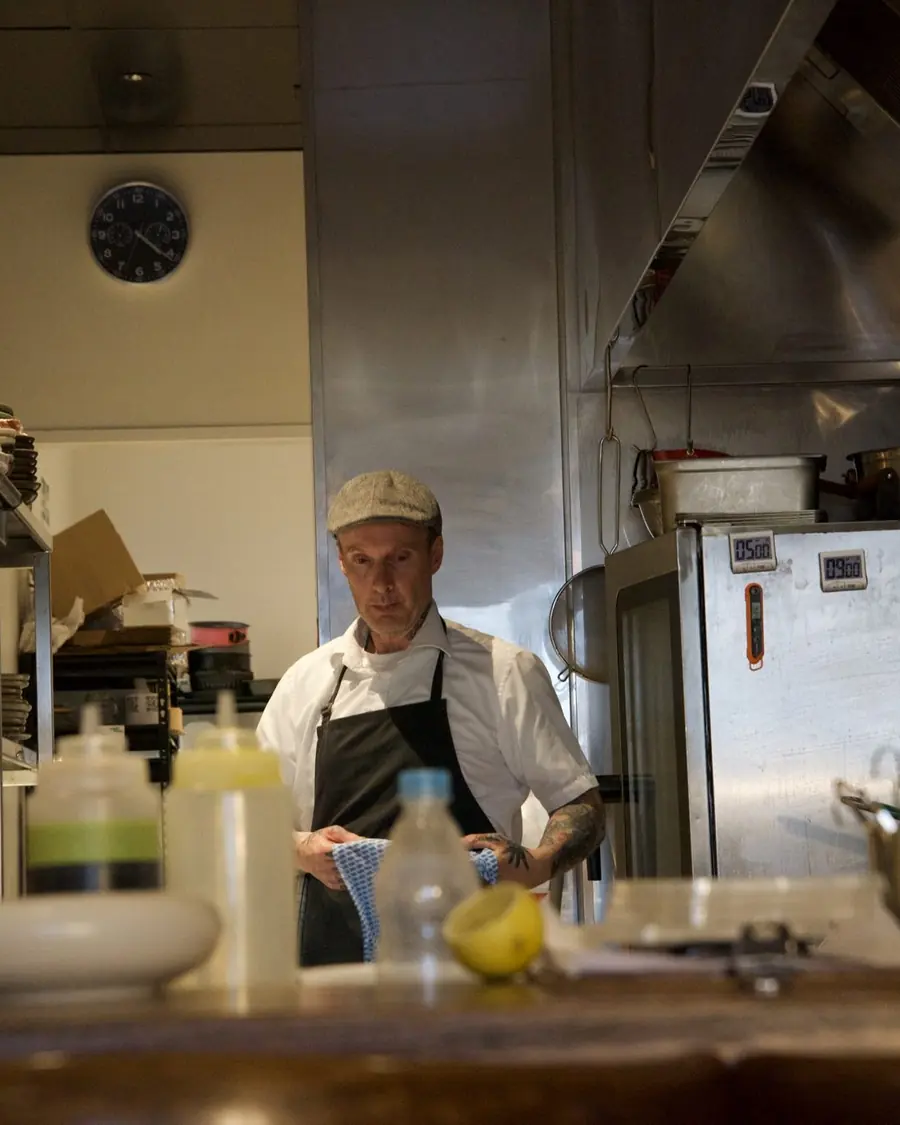 A chef at the bench among the squeeze bottles