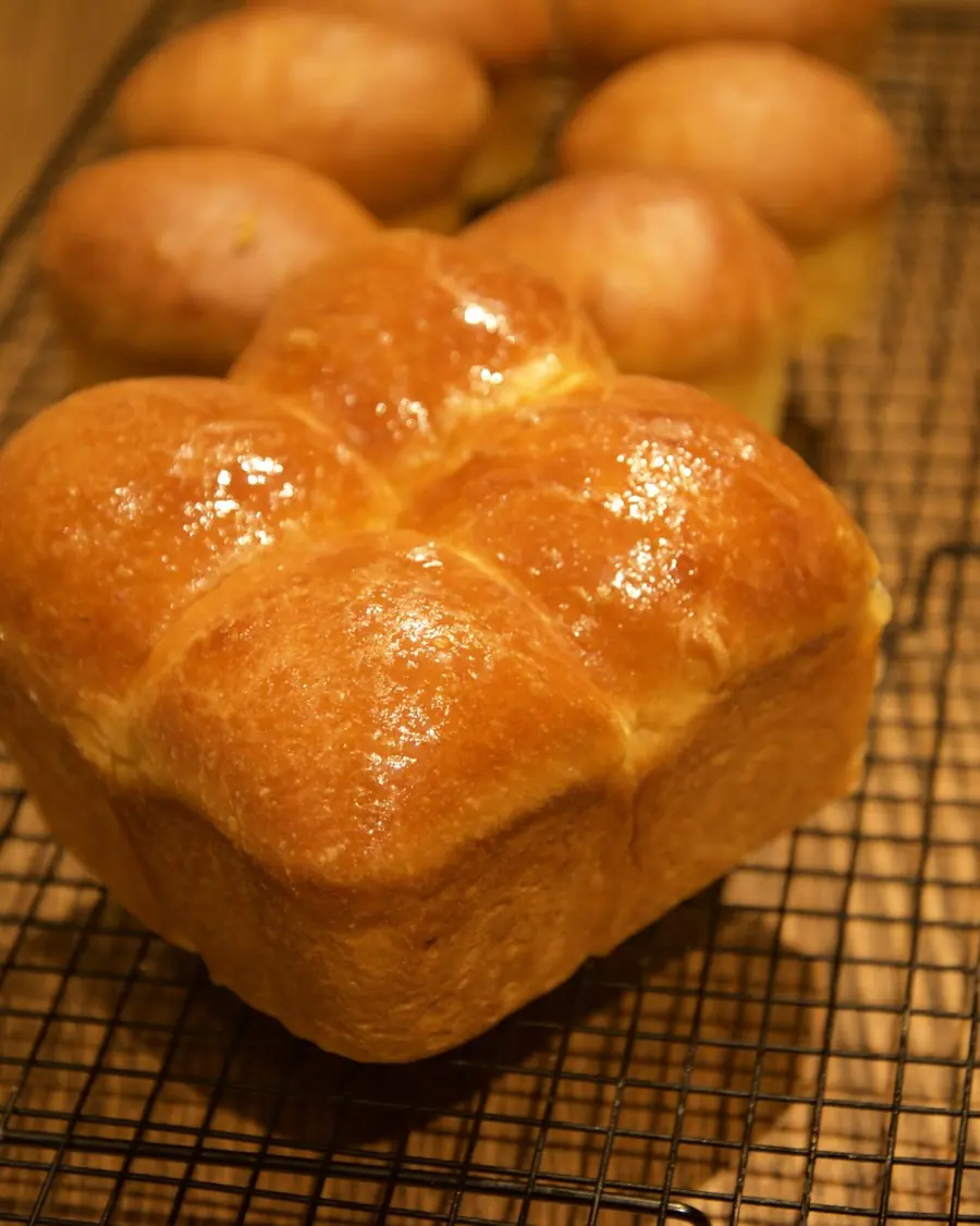 Brioche buns, glazed and cooling on a wire rack