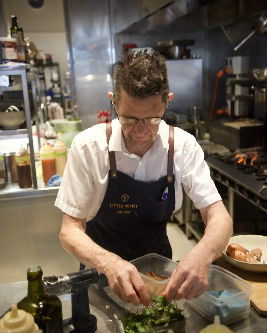 A chef plating, hands in the greens